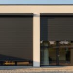 Volets roulants gris anthracite : une solution déco pour mieux limiter la chaleur pendant la canicule Façade de maison contemporaine avec volets roulants gris anthracite fermés, éclairage chaud d’été et rendu architectural soigné.